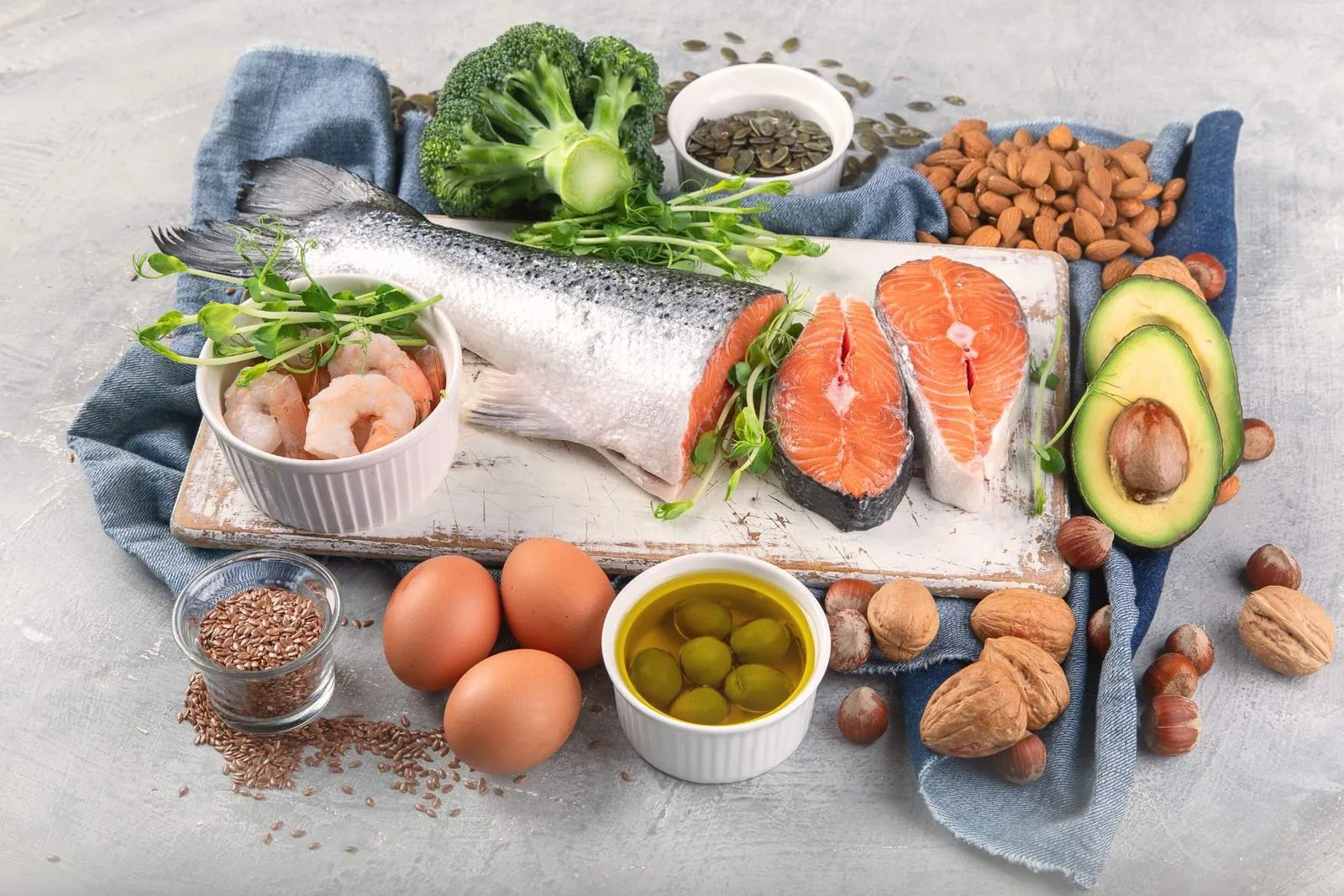 Still life with a fillet of salmon, eggs, avocado, walnuts, seeds and olives on a board