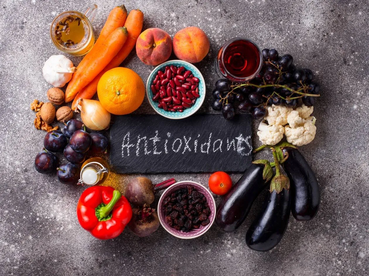 Colourful fruit and vegetables arranged in a circle around a blackboard with the word "Antioxidants"