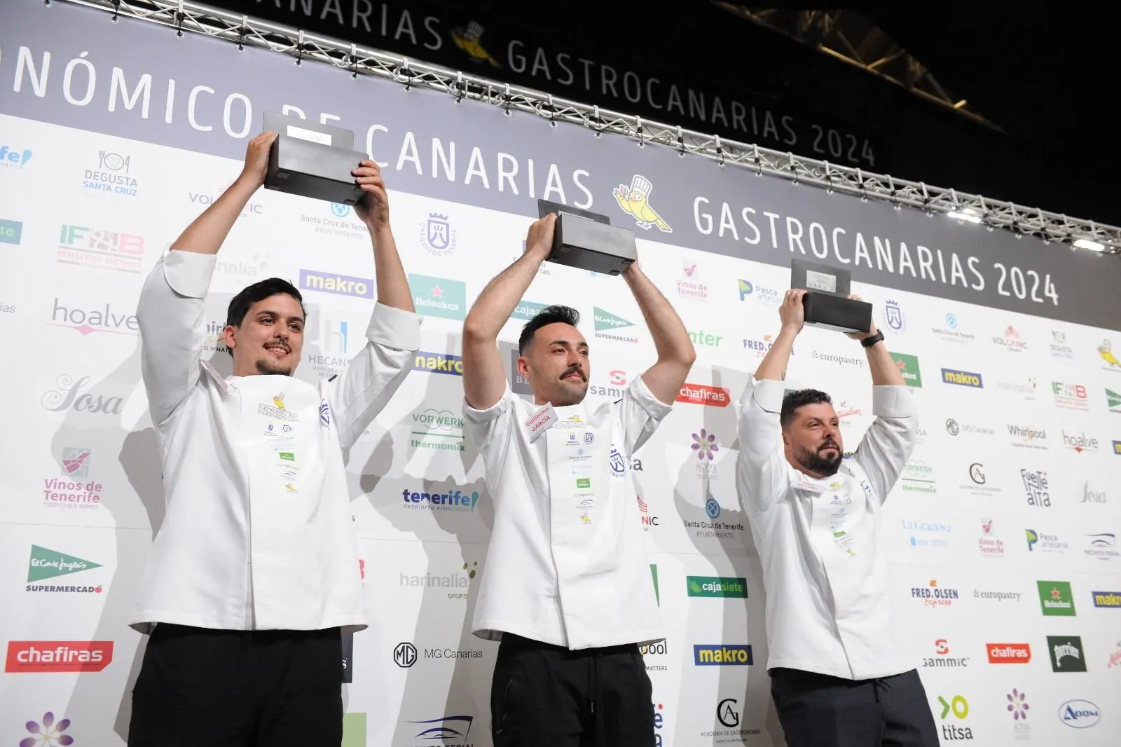 The three prize winners raise their trophies in front of the GastroCanarias 2024 photocall