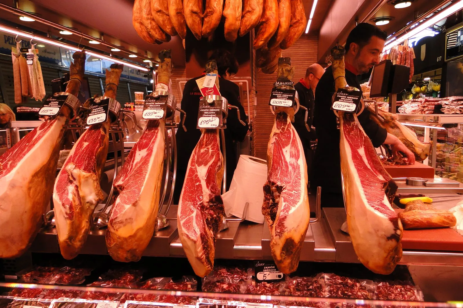 Jamones ibéricos colgados en un puesto del mercado de la Boquería, en Barcelona