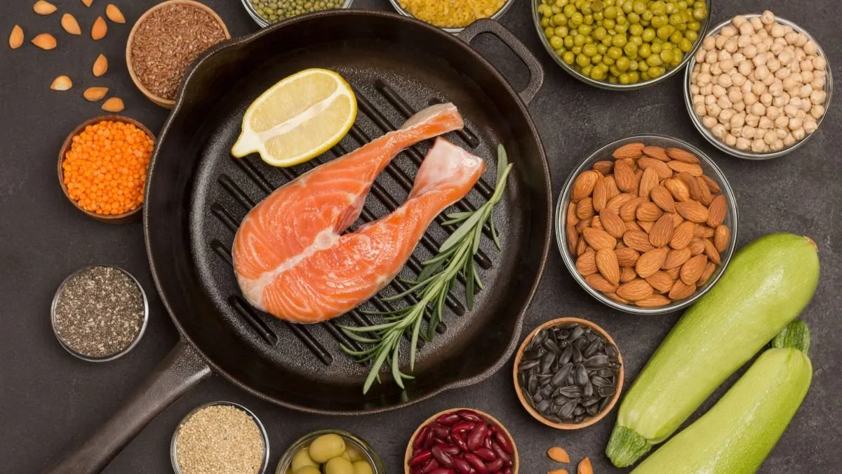 Salmon fillet with lemon in a griddle pan, surrounded by bowls of pulses, seeds and nuts