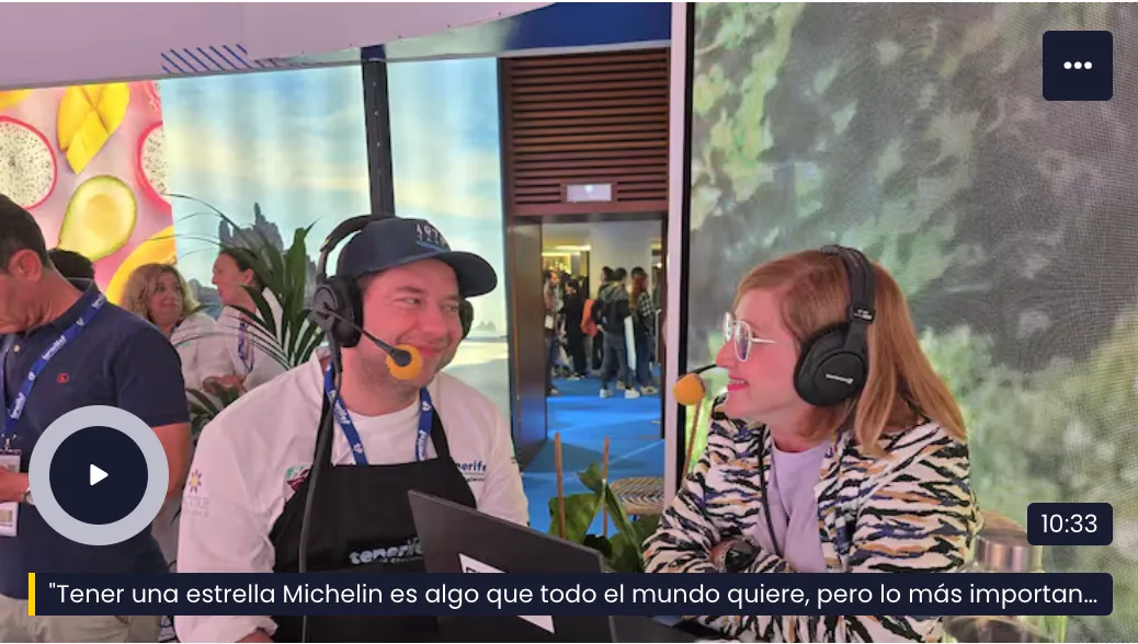 Diego Schattenhofer, wearing headphones, interviewed by a journalist at the Tenerife stand