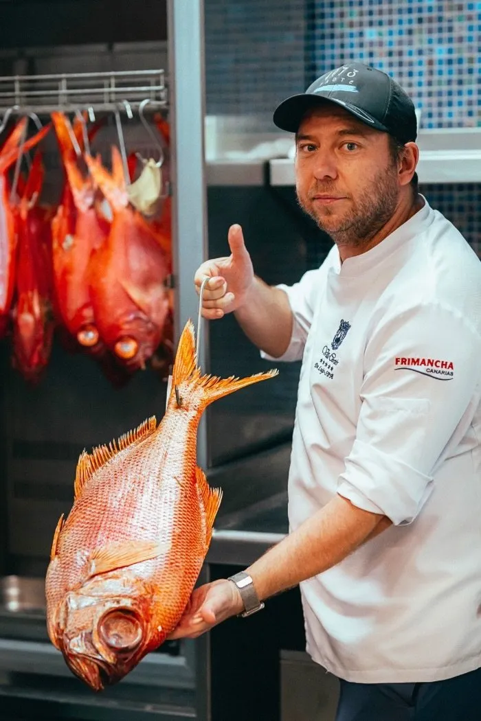 Diego Schattenhofer holds a whole fish beside the ageing chamber