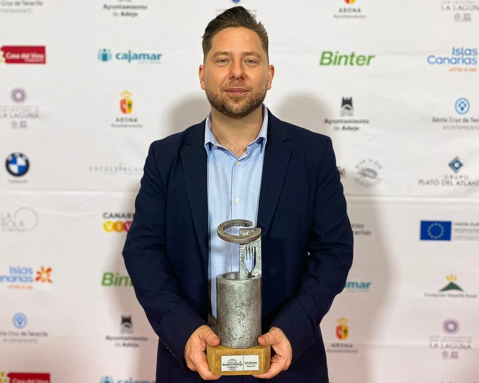 Diego Schattenhofer sostiene el trofeo del premio Consume Canario 2022 ante el photocall