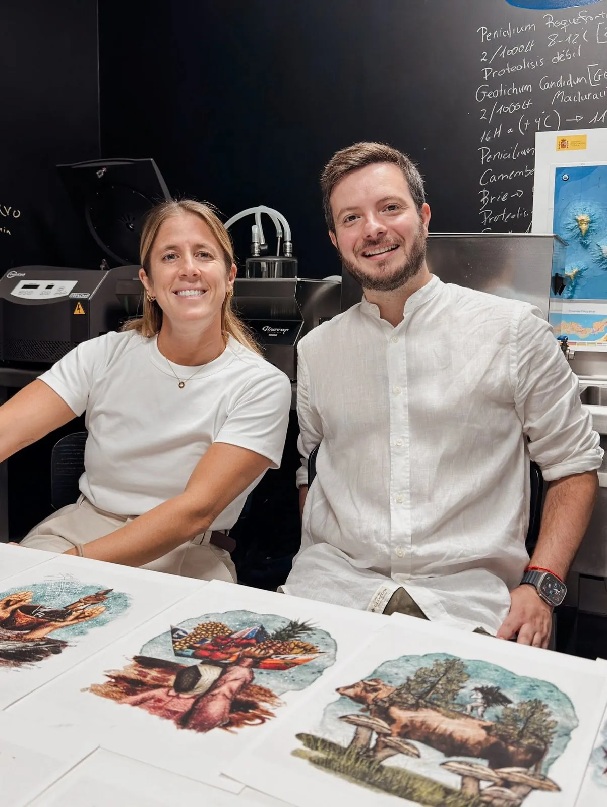 Two of the participants in the working day, sitting in front of the blackboard in Taste 1973’s R&amp;D&amp;i room, with the maturation notes written in chalk and illustrated sheets on the table