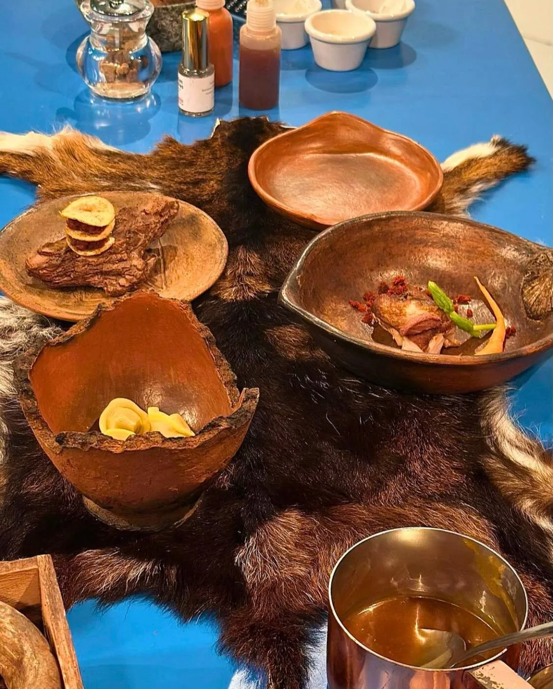 Dishes of matured goat served in clay bowls on a goat hide