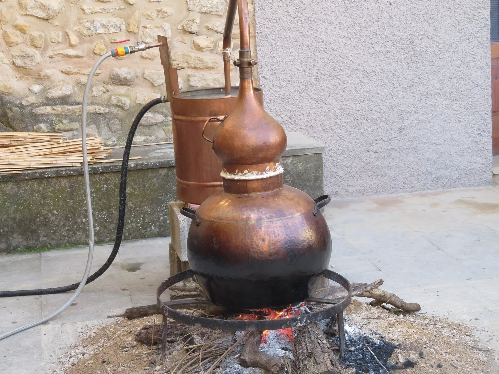 Copper still over the fire, distilling wine spirit