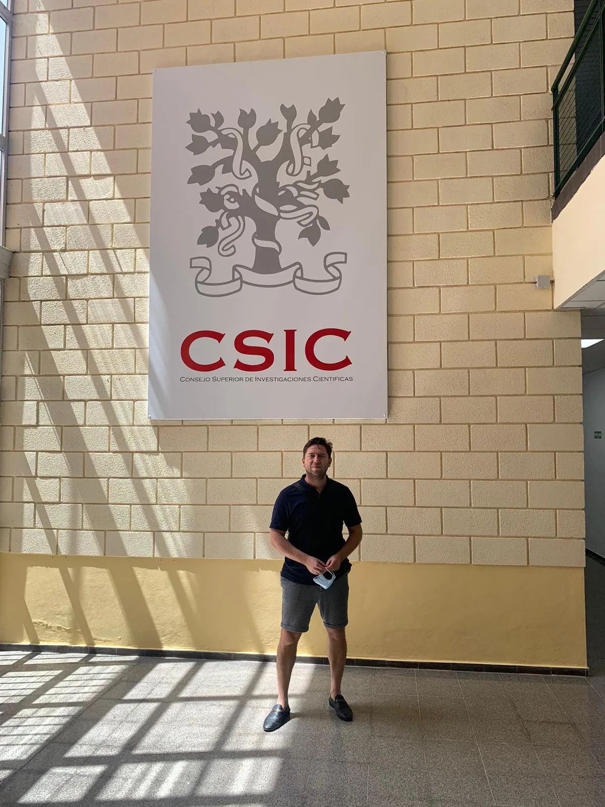 Man posing under the CSIC sign in the lobby of the research centre
