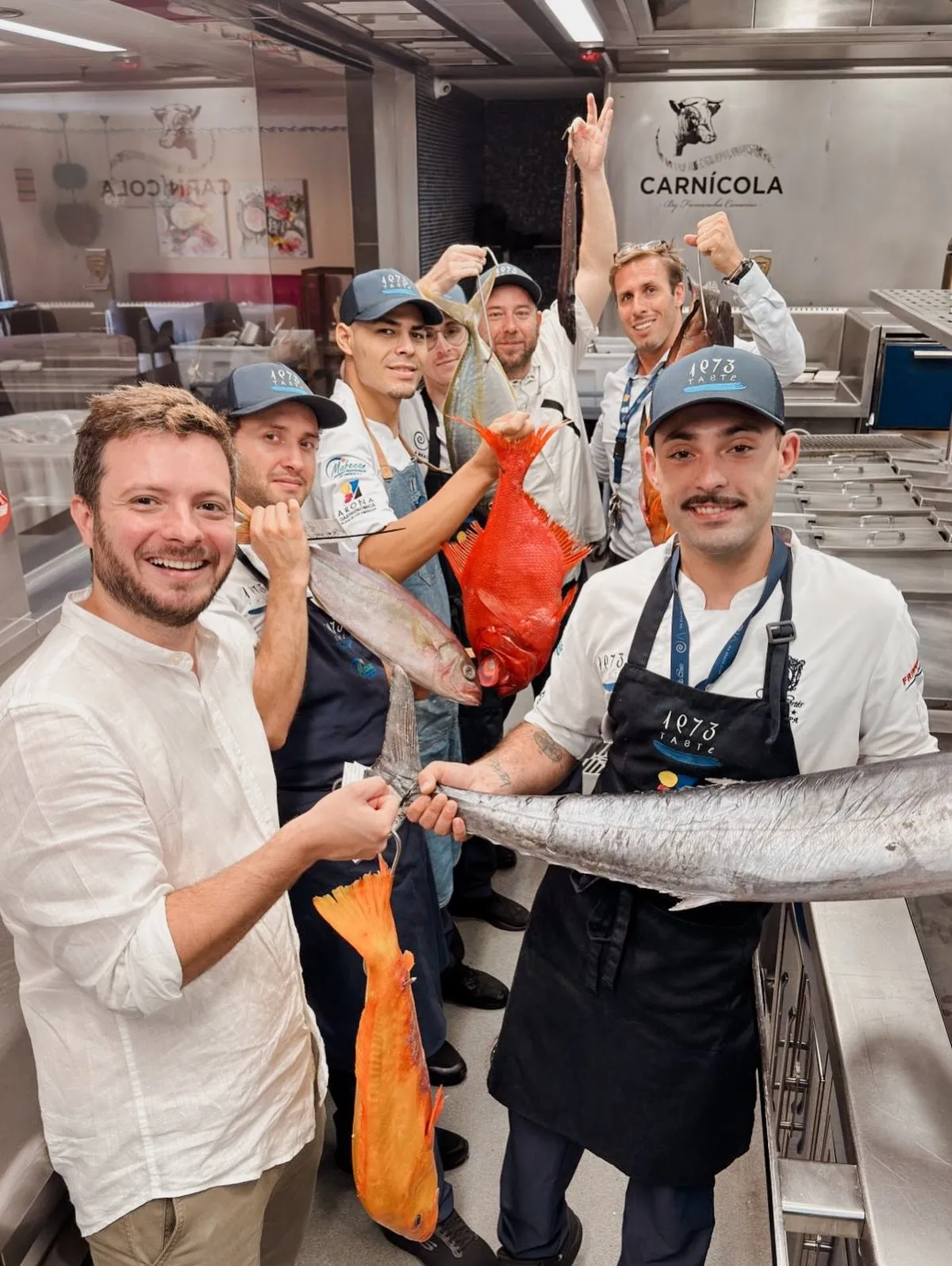 The Taste 1973 kitchen team, in the house’s caps and aprons, hold up several fresh Canary Islands fish in the work area where the fish was reviewed