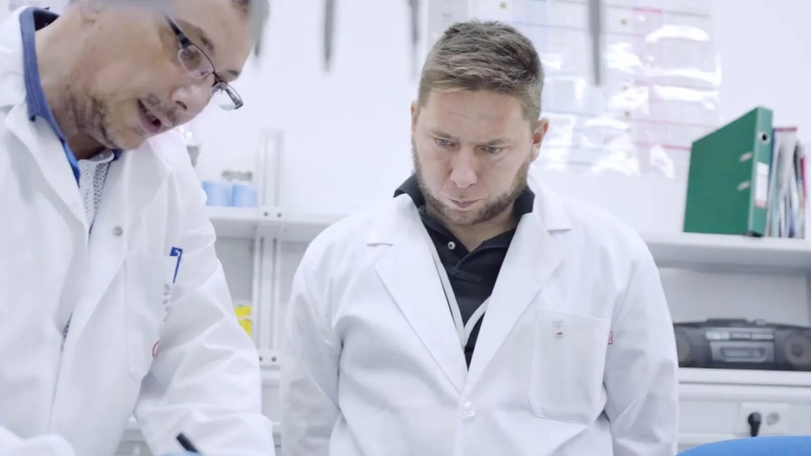 Diego Schattenhofer, wearing a white lab coat, alongside a researcher in a laboratory