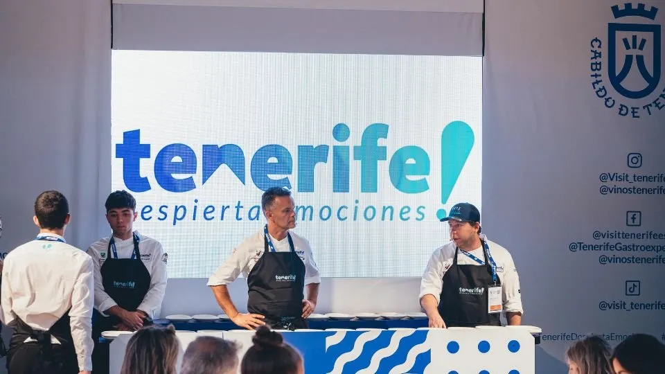 Chefs wearing Tenerife aprons in front of the island’s tourism logo on screen