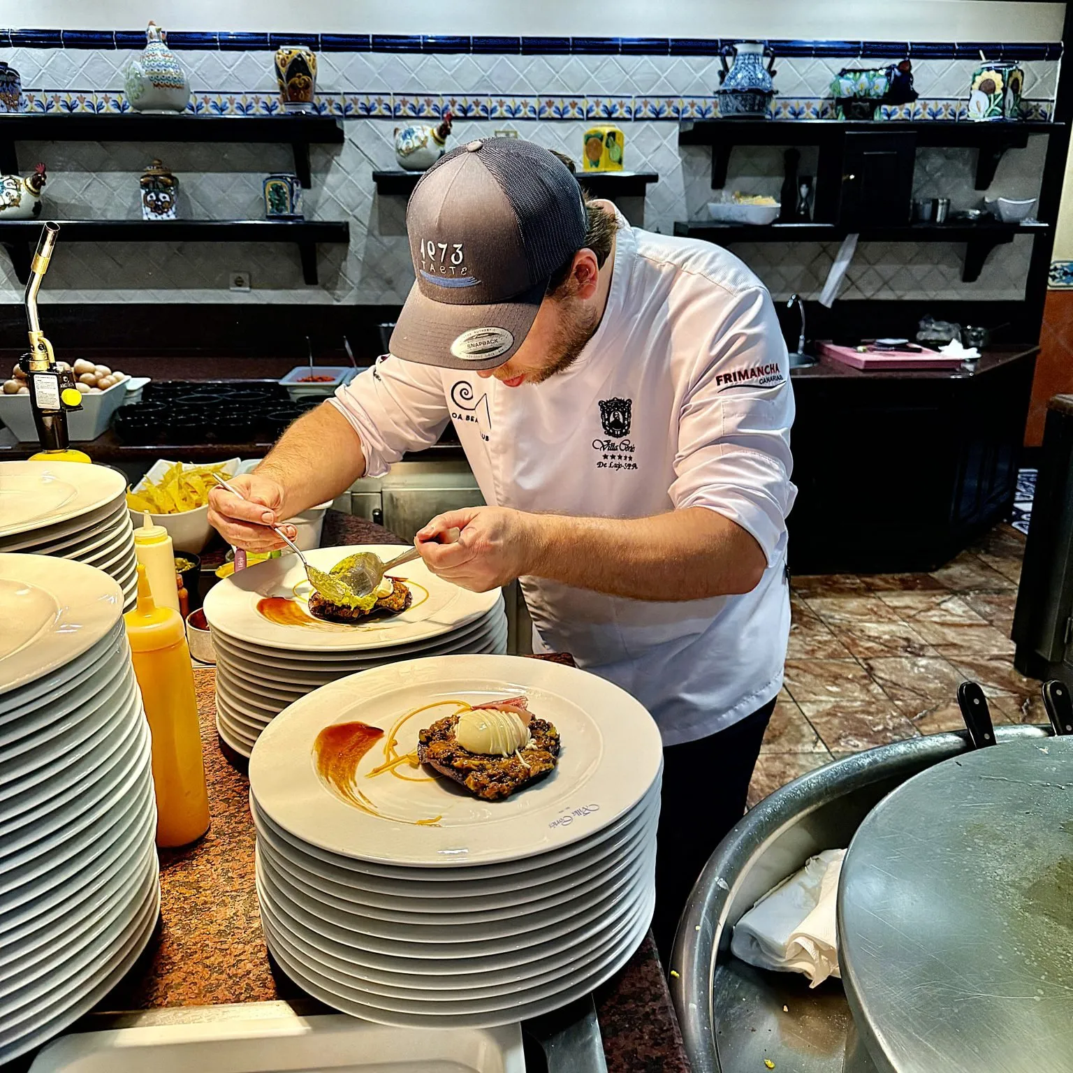 Member of the team plating eggs on a crispy base in the kitchen