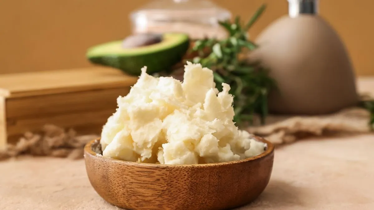 Wooden bowl with whipped goat butter, avocado and fresh herbs in the background