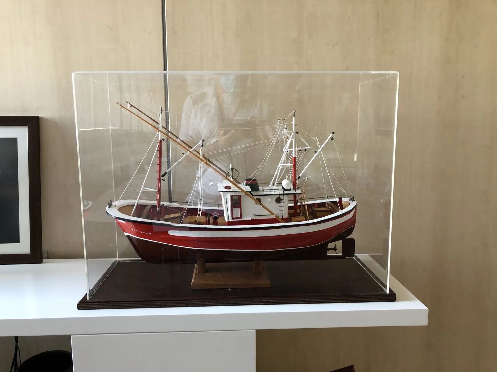 Model of a red-hulled fishing boat protected inside a methacrylate case