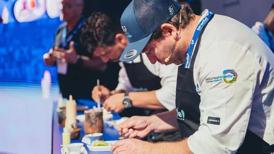 Diego Schattenhofer plating with tweezers alongside another chef on the Gastronomika stage