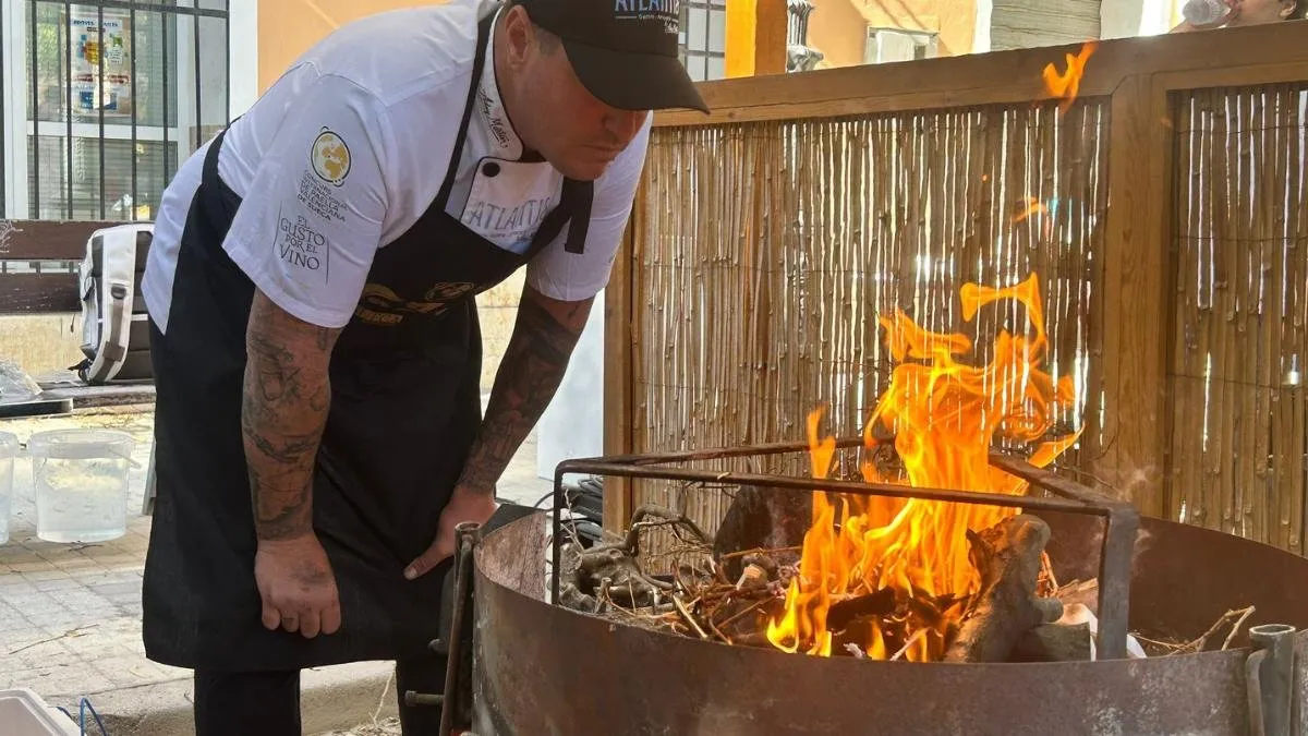 Aday Martín stokes the wood fire at the stand during the Sueca competition