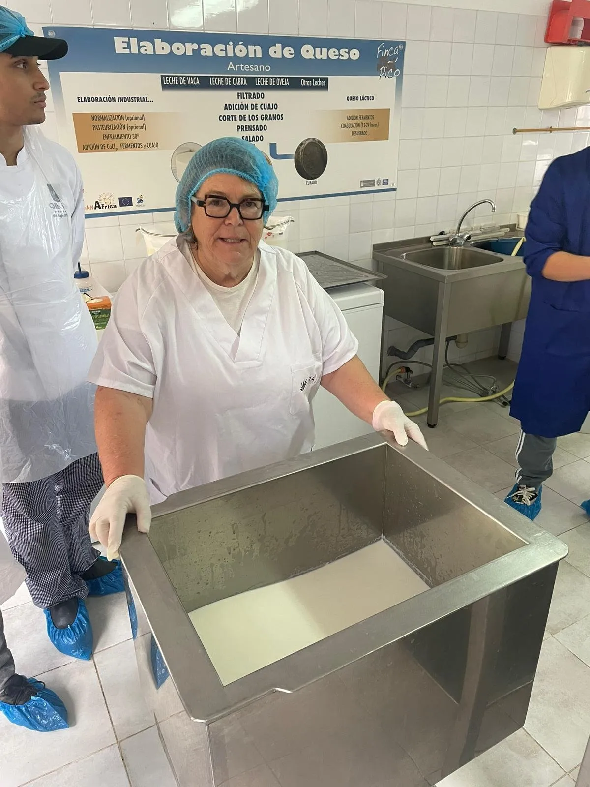 Cheesemaker beside the curdling vat under an artisan cheesemaking display panel