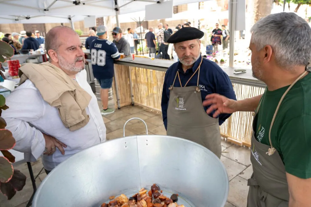 Two chefs stirring a huge pot of stew at a Comida Popular stall