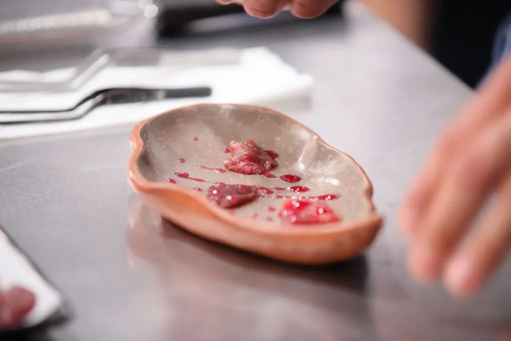 Shell-shaped ceramic dish with small pieces of meat in sauce