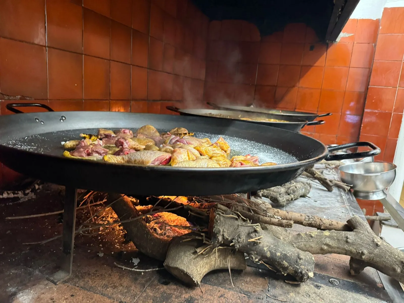 Chicken and rabbit searing in the paella over the wood embers