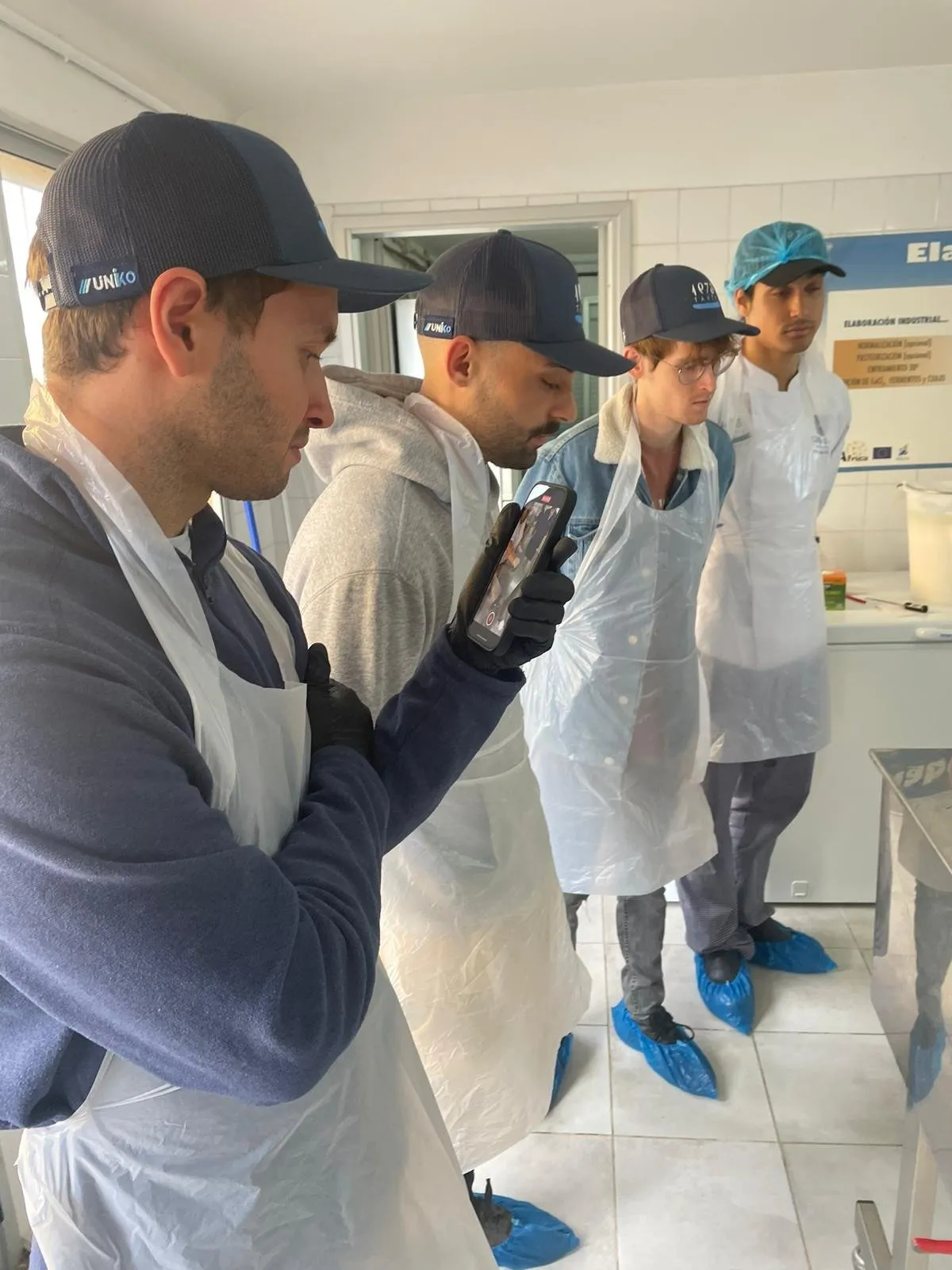 Visitors in disposable coats listening to the explanation in the production room