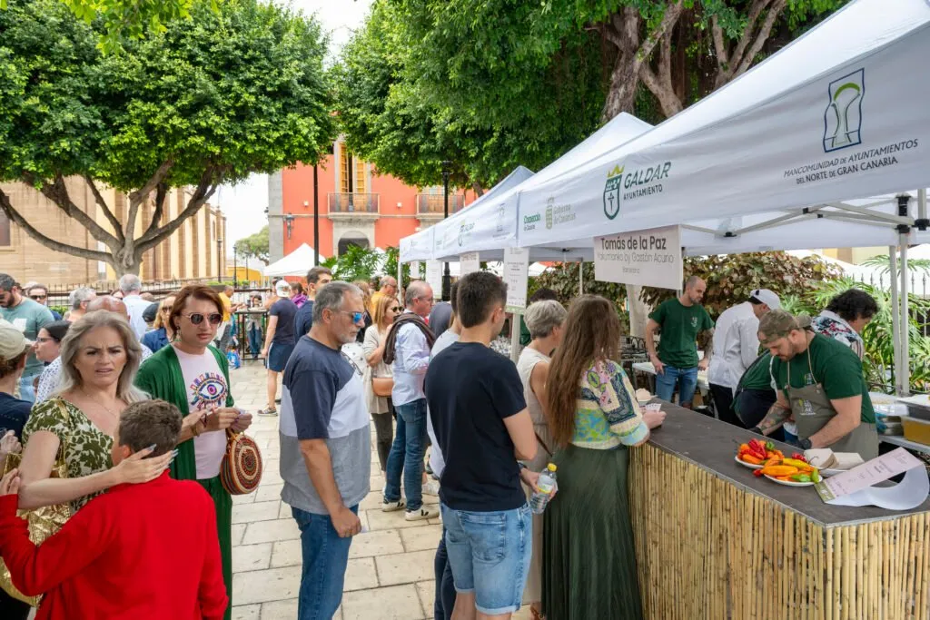 Attendees chatting in front of a stall, with chefs working in the background