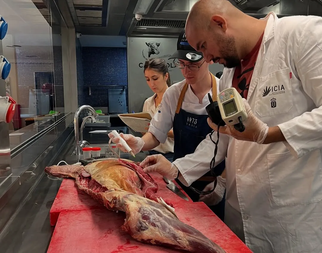 ICIA technicians in lab coats measure a goat carcass on the butchery table
