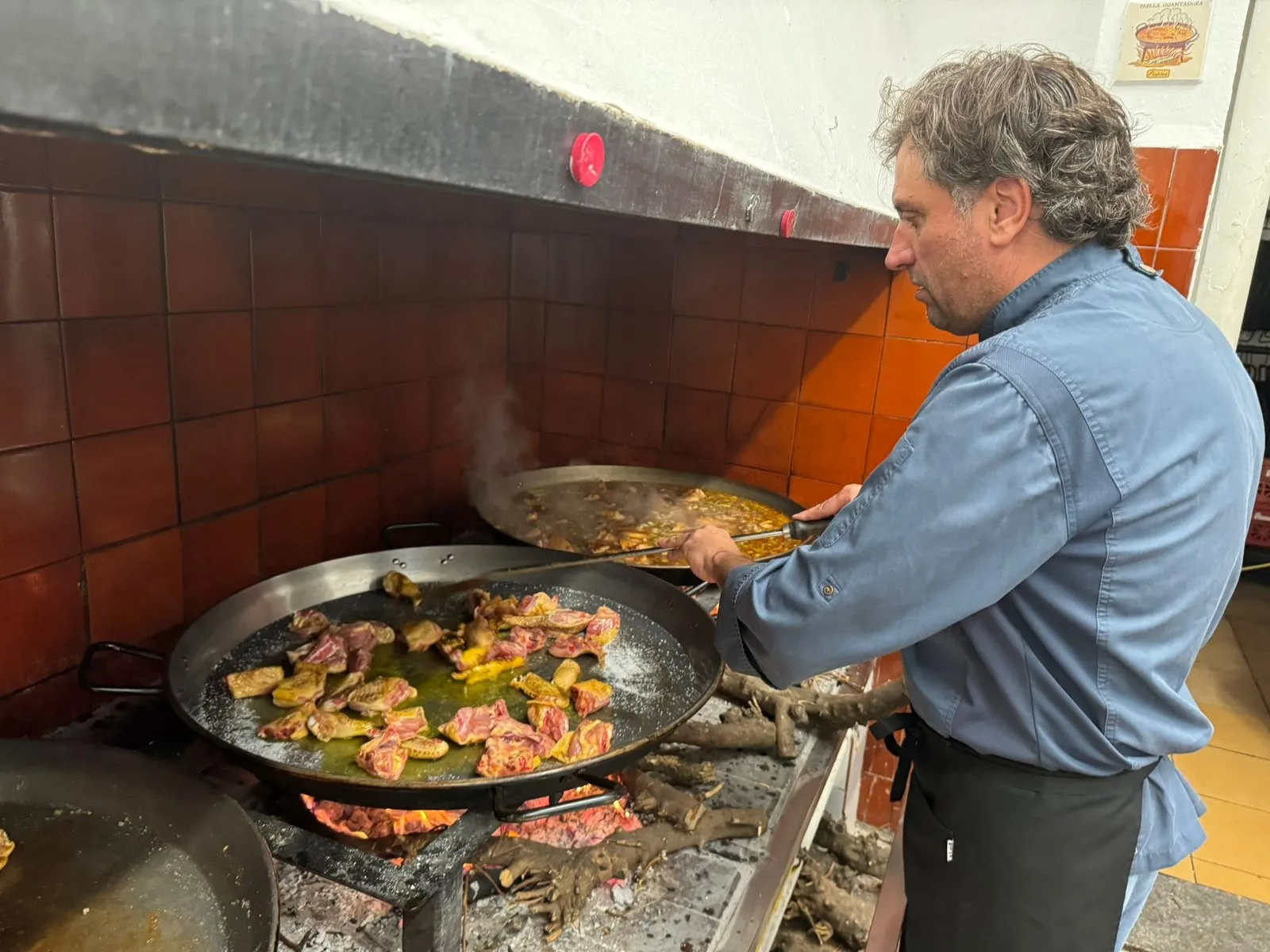 Vicente Rioja sautés the meat in the paella over the wood fire