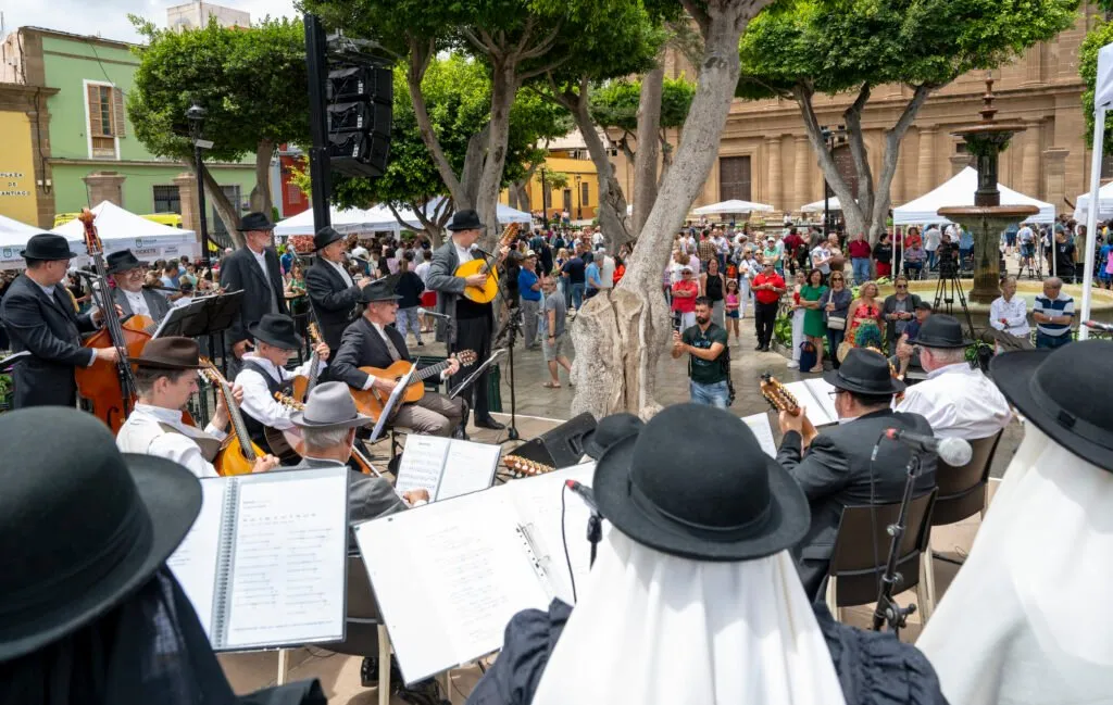 A folk group in traditional dress performs in the square, surrounded by a crowd