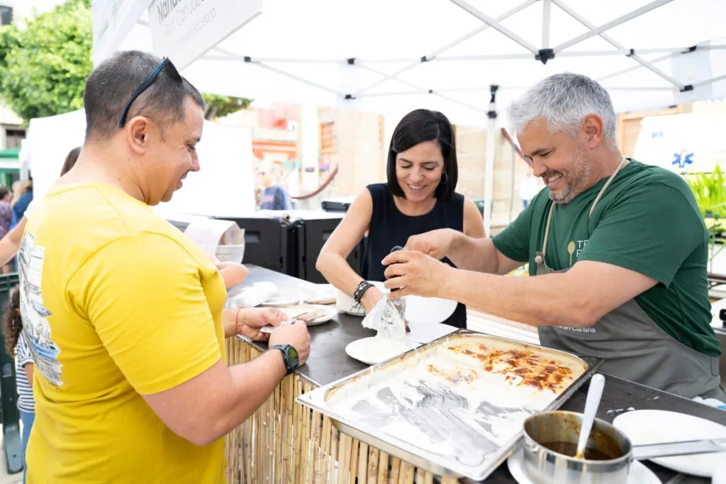 Three chefs plating up on the wooden counter of one of the stalls