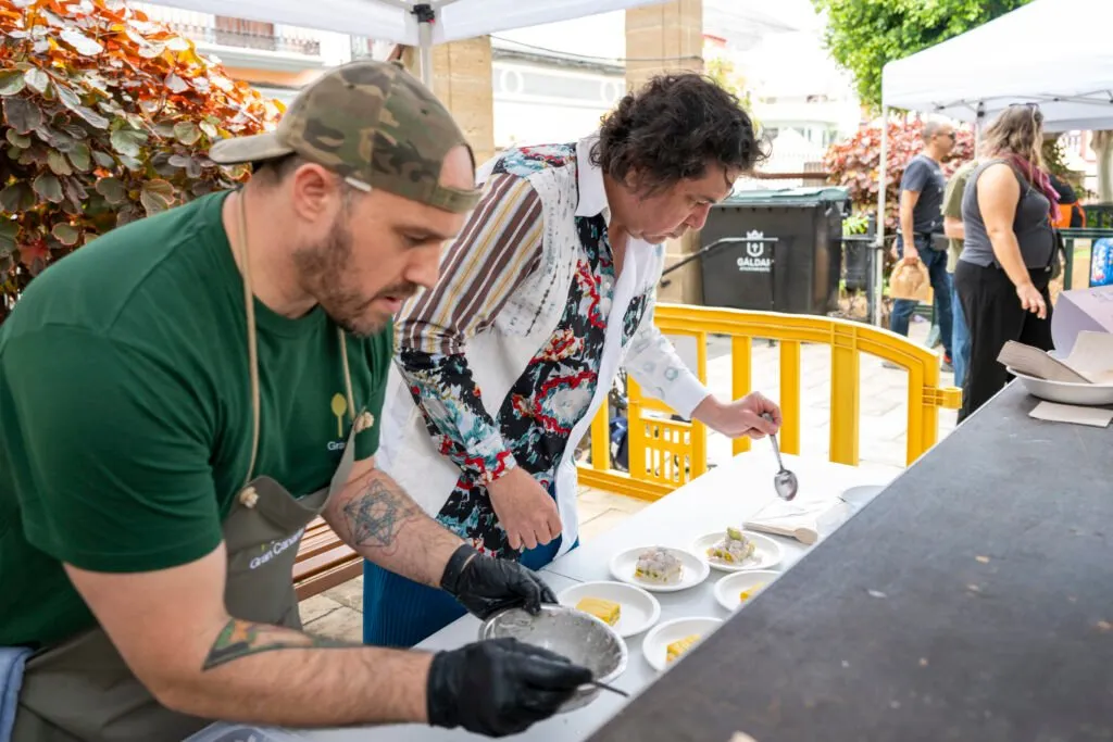 Two chefs finish off the plates on the counter at the same time
