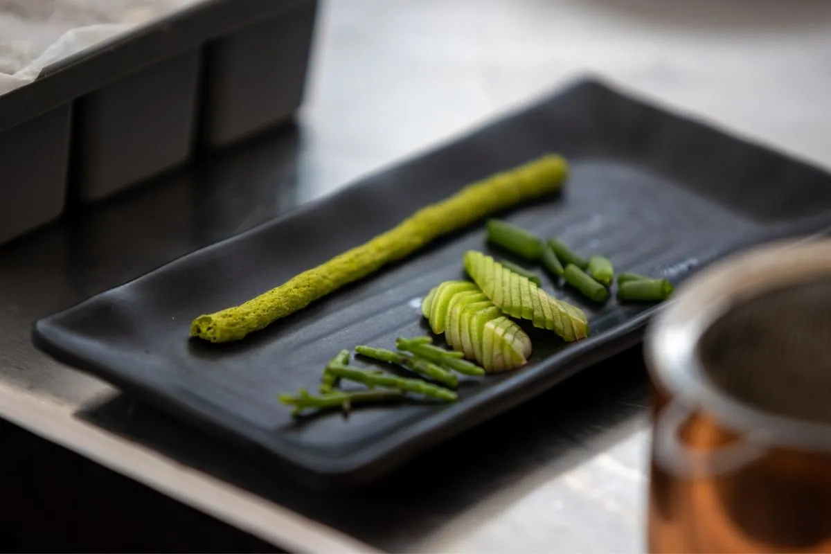 Whole and sliced green asparagus on a black tray
