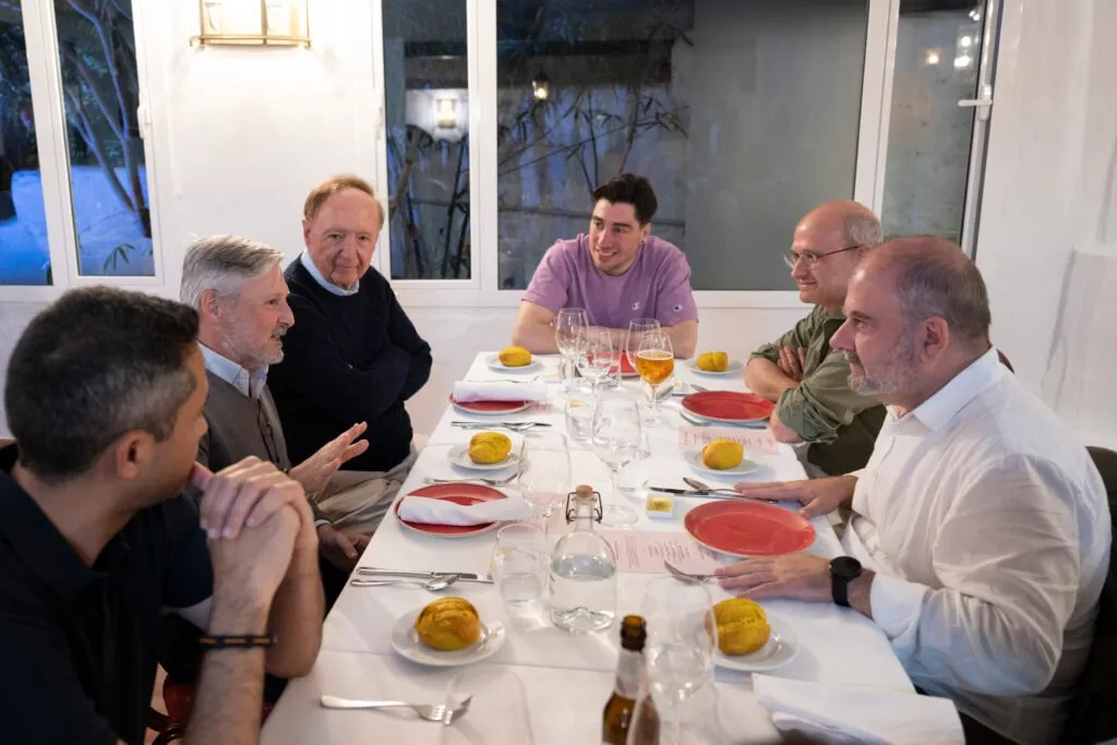 Guests chatting around the table with glasses and plated dishes
