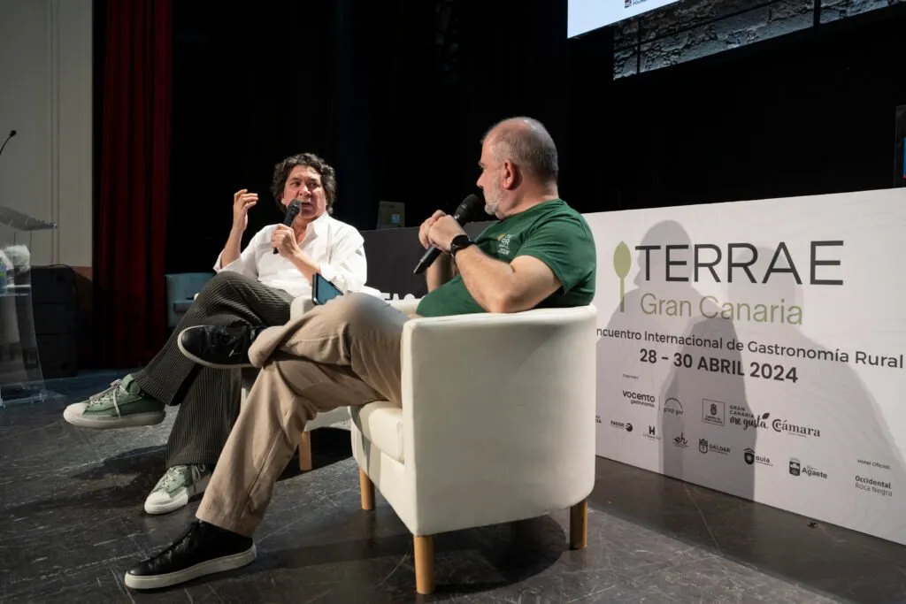 Gastón Acurio talking, seated on stage in front of the Terrae sign