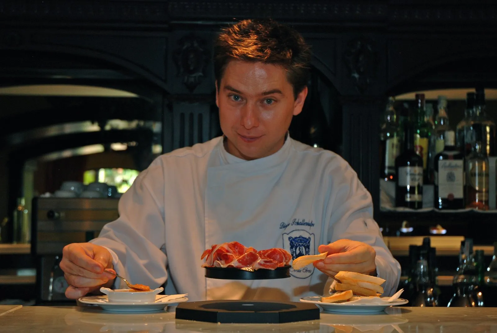 Diego Schattenhofer, holding a spoon and a piece of toast, in front of an Iberian ham tapa levitating on the base of the UFO.OD