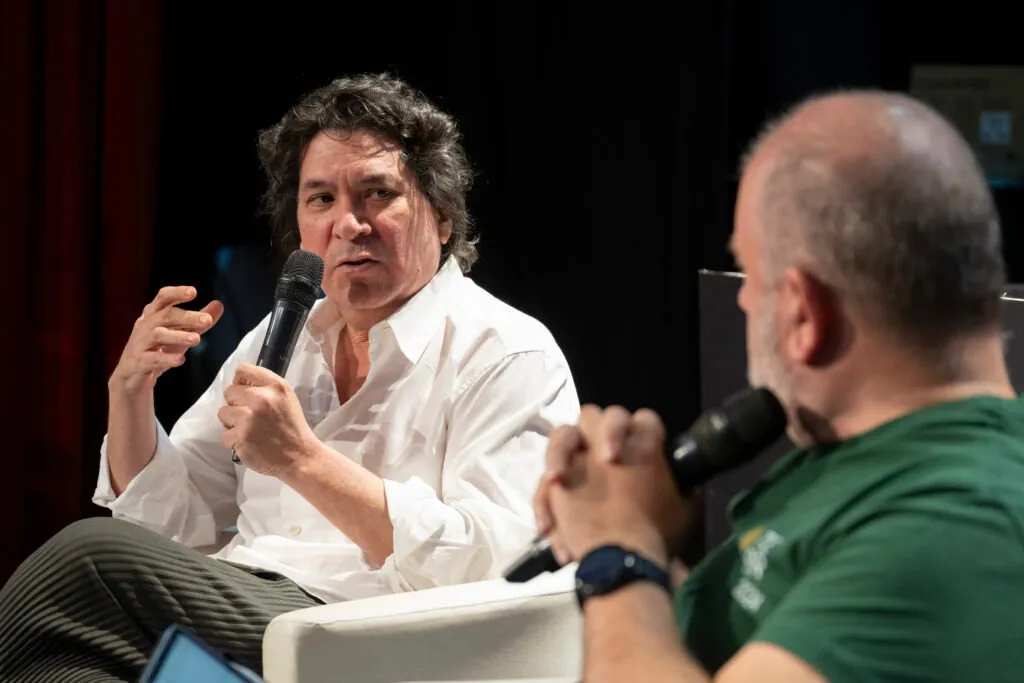 Gastón Acurio speaking, microphone in hand, next to his interlocutor
