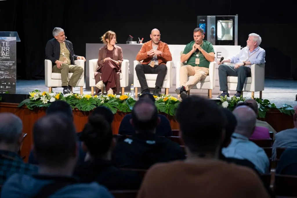 Five participants at a round table on the theatre stage