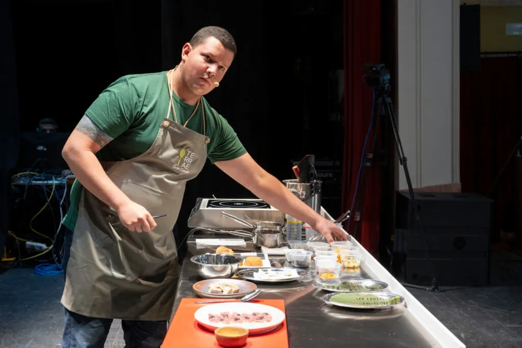 A chef preparing a dish in the kitchen set up on the stage
