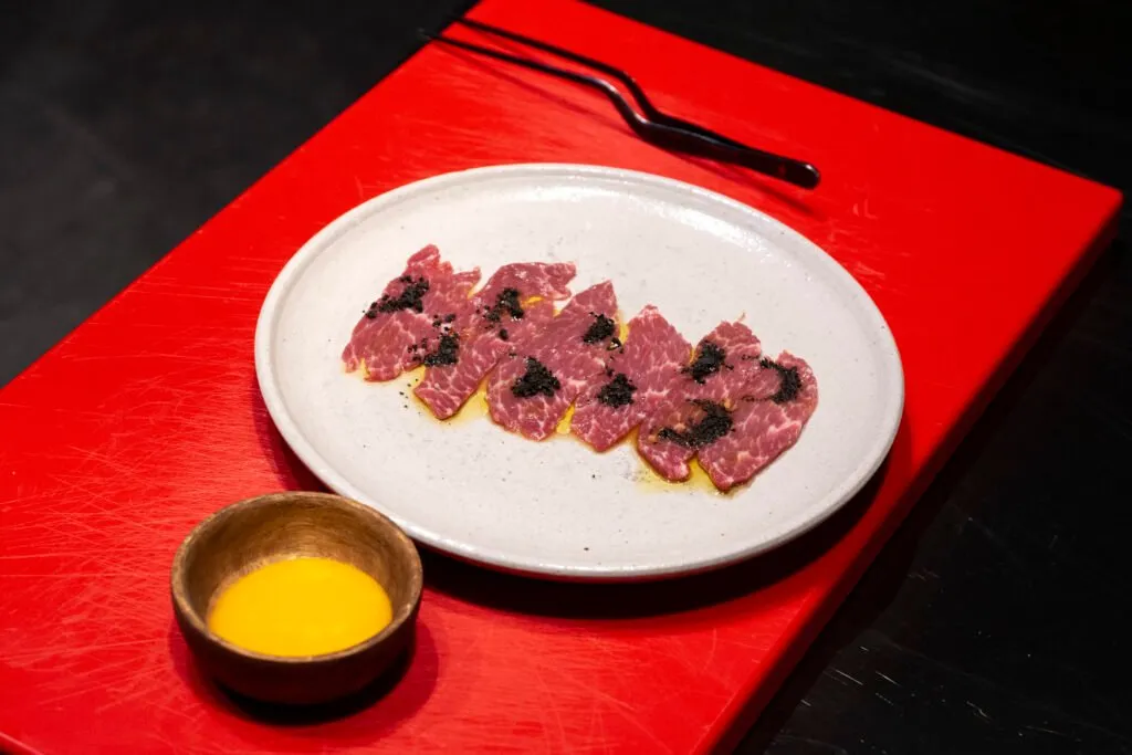 Slices of raw meat with egg yolk on the work board
