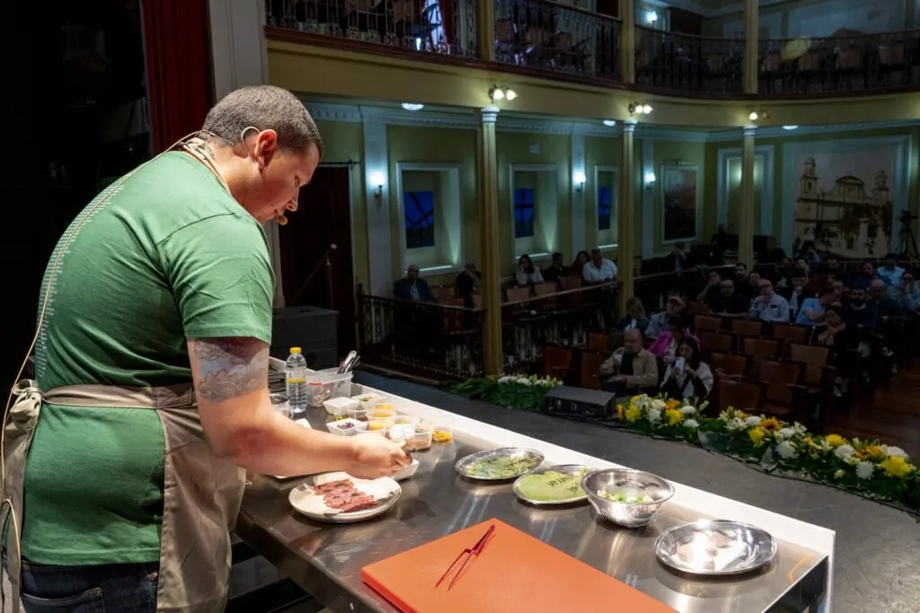 A chef plating up on stage in front of the theatre audience