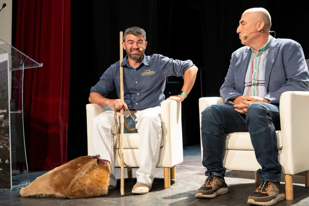 A livestock farmer with his crook talking to another participant on stage