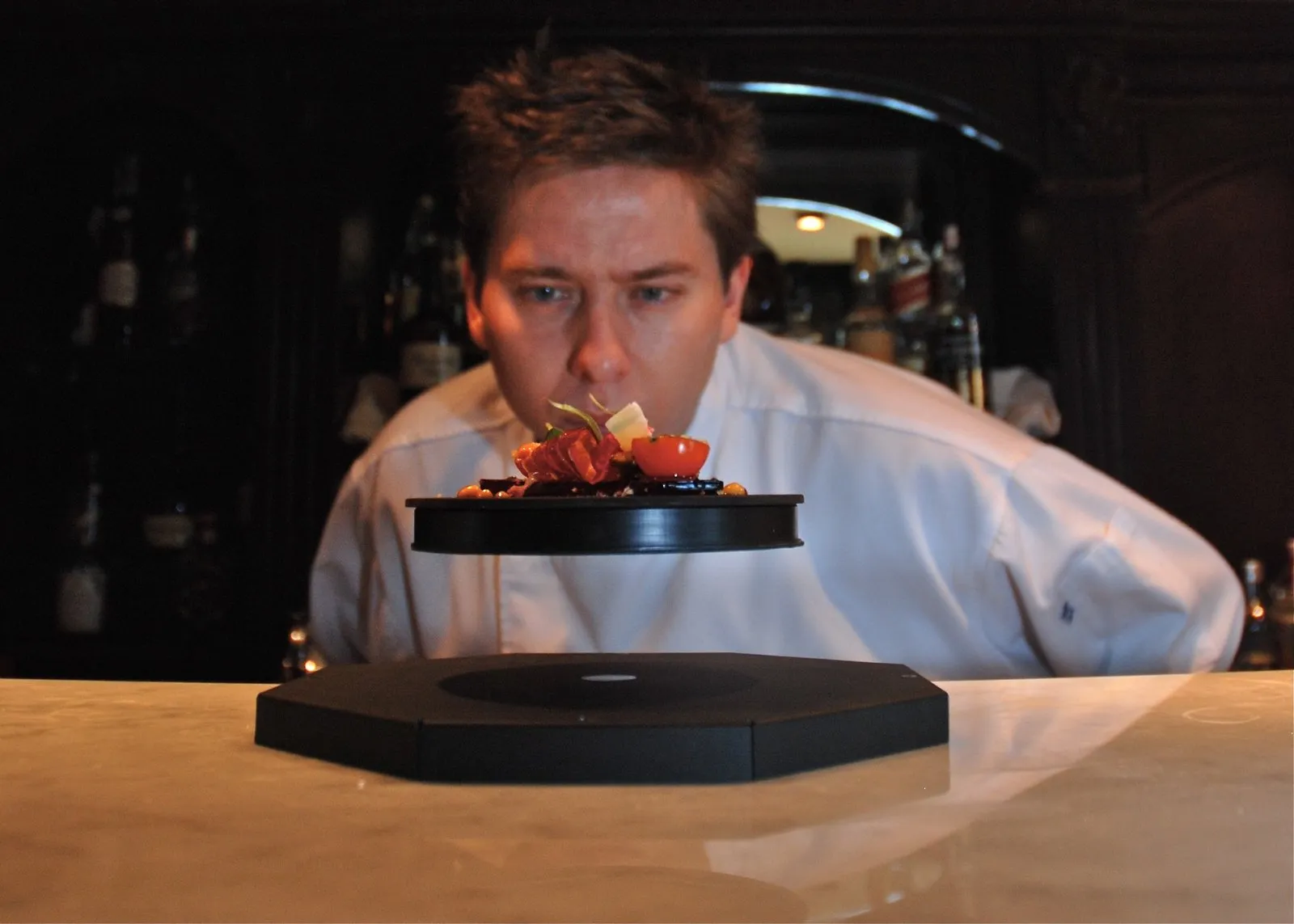 Diego Schattenhofer looks at a dish suspended over a black base during an Astrochefs team demonstration