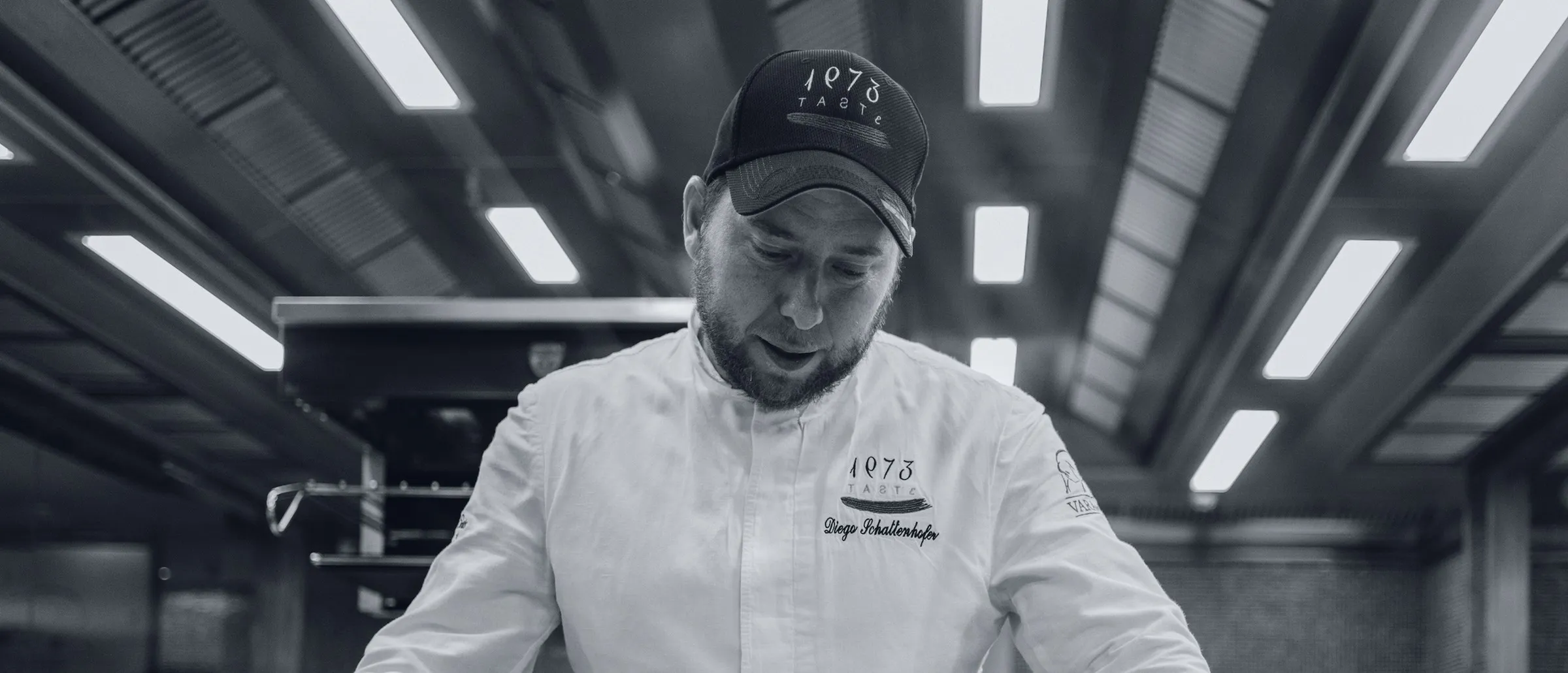 Diego Schattenhofer, wearing the Taste 1973 chef's jacket, working at the kitchen pass