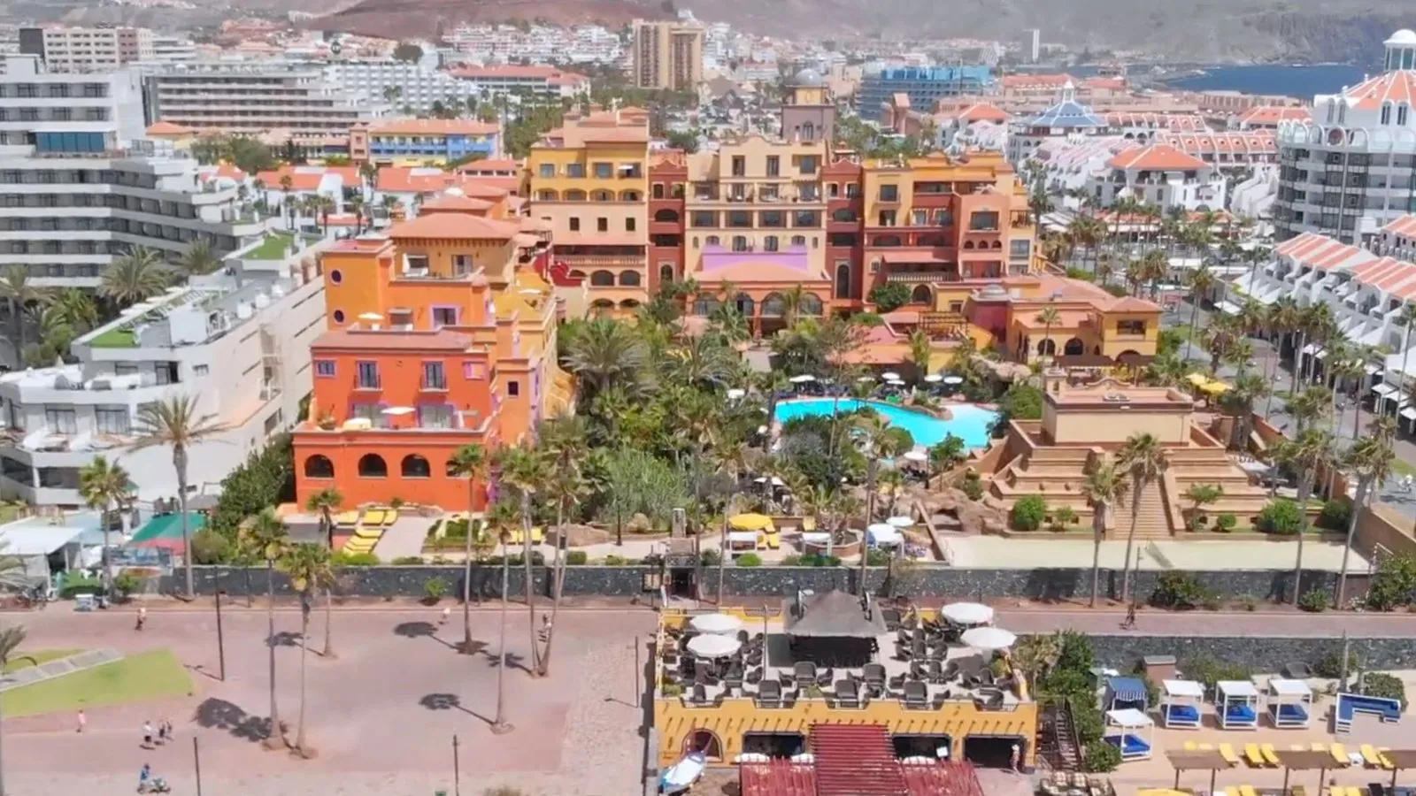 Aerial view of the Hotel Villa Cortés, with its coloured buildings, palm trees and pool, facing the Atlantic Ocean