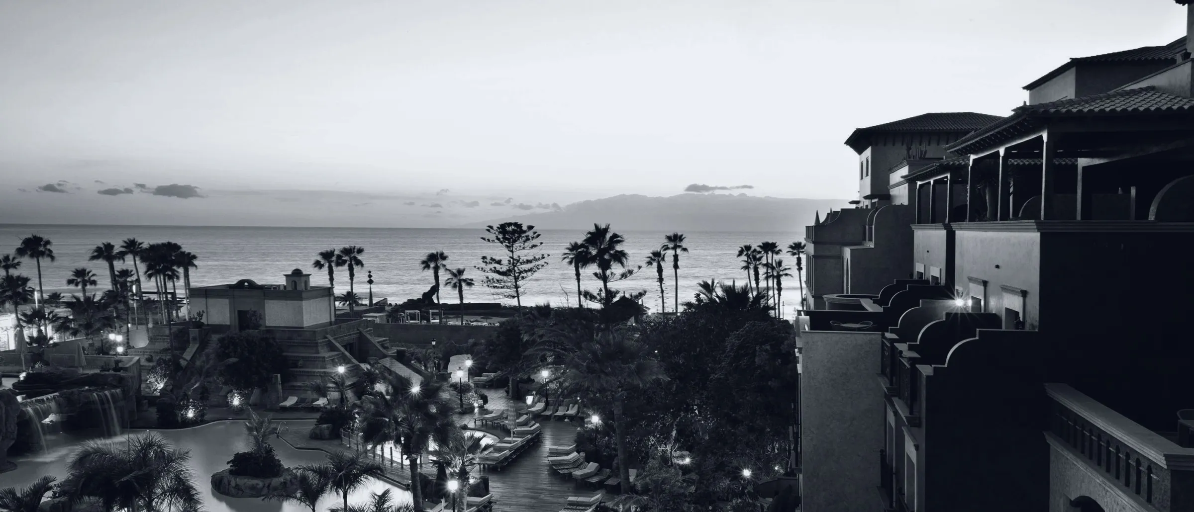 View of Hotel Villa Cortés at sunset, with the pool, the palm trees and the Atlantic in the background