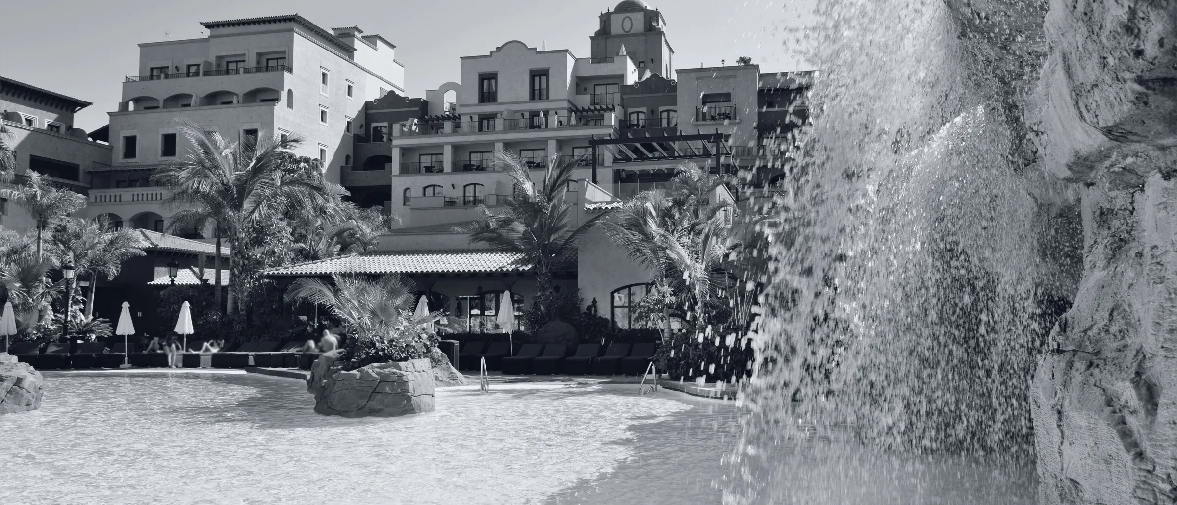 Façade, palm trees and waterfall pool of the Hotel Villa Cortés