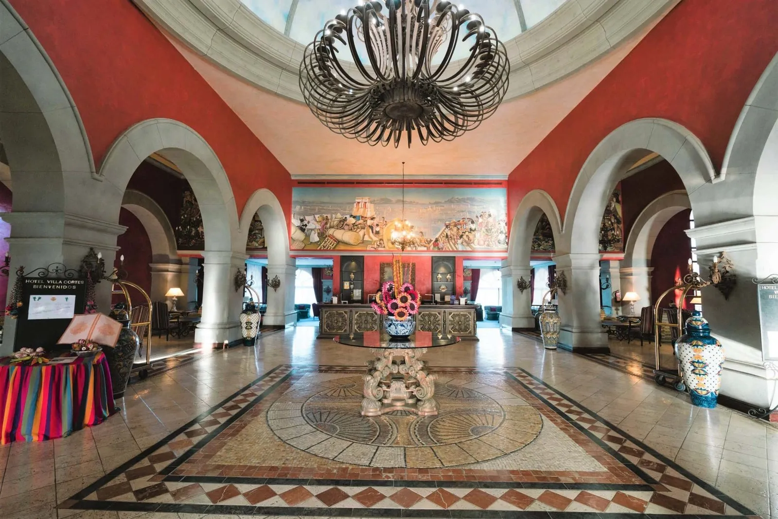 Entrance hall of the Hotel Villa Cortés: dome, wrought-iron lamp, reception desk and mosaic floor